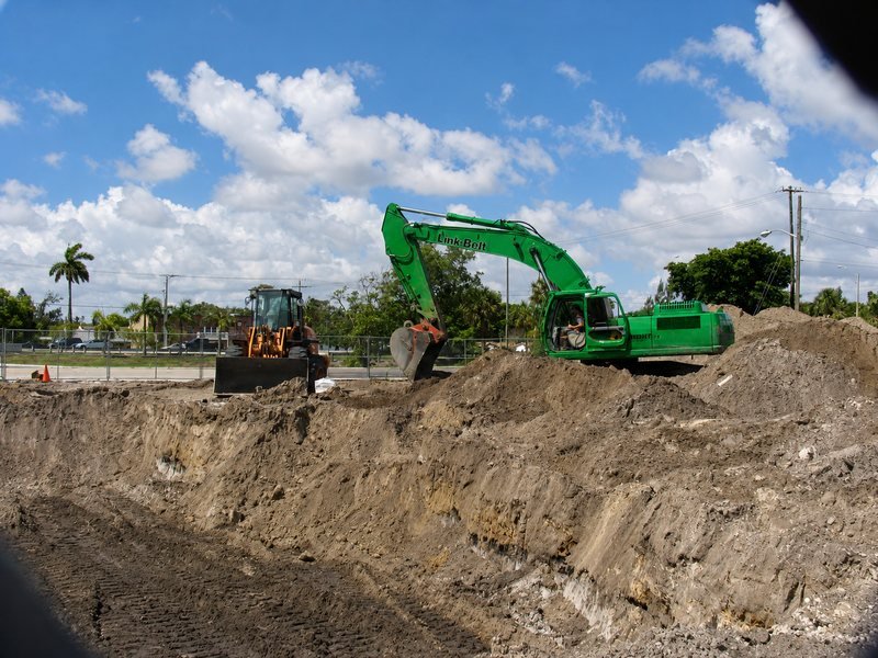 Green excavator working at an open excavation