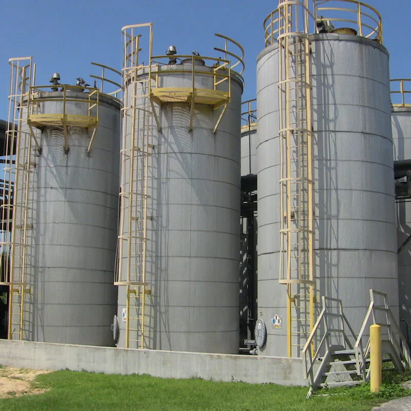 Vertical steel storage tanks with access ladders at an industrial facility